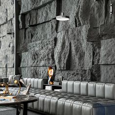 a living room filled with furniture next to a stone wall covered in black and white tiles