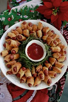 a white plate topped with pigs in a blanket next to a bowl of ketchup