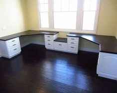 an empty room with white cabinets and black counter tops on the floor, in front of a window