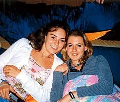 two women sitting next to each other on top of a blue couch in a living room