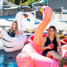 two women are sitting on inflatable flamingos at the pool while another woman holds a drink