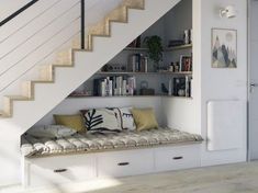 there is a bench under the stairs in this living room with built - in bookshelves