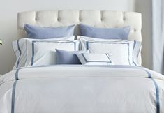 a bed with blue and white sheets and pillows