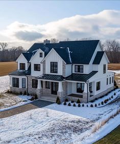 a large white house sitting in the middle of a snow covered field