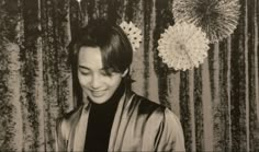 a black and white photo of a woman with flowers in her hair smiling at the camera