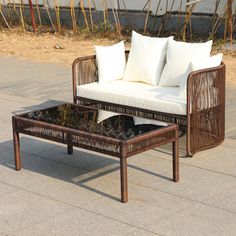 a wicker coffee table with white pillows on it sitting in front of a building