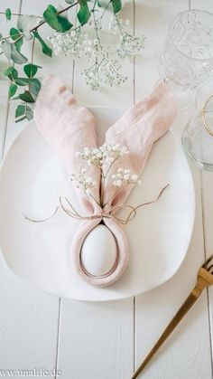 a white plate topped with a pink napkin and an egg shell on top of it