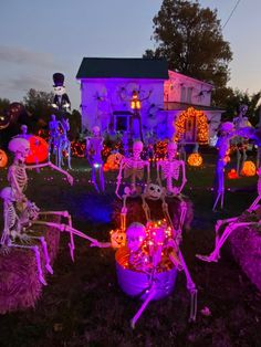 halloween decorations in front of a house with skeletons and pumpkins on the lawn at night