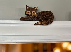 a wooden fox figurine sitting on top of a window sill next to a wall