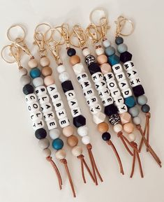 several different types of beaded keychains on a white surface with gold chains