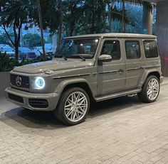 a grey mercedes g - class parked in front of a building