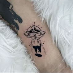 a black and white photo of a cat in an alien ship tattoo on the leg