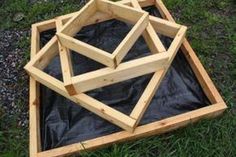 three wooden structures sitting in the grass on top of plastic tarp next to each other