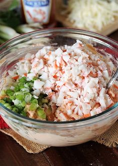 a glass bowl filled with chopped vegetables on top of a wooden table next to other ingredients