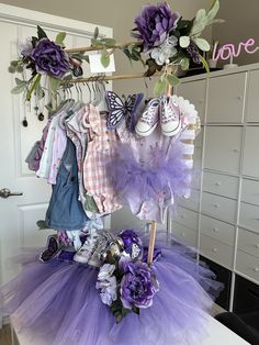 a bunch of baby clothes hanging on a rack in a room next to a dresser