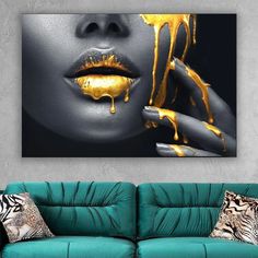 a woman's face with yellow dripping paint on her lips and hands, in front of a green couch