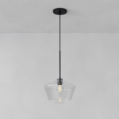 a clear glass light fixture hanging from a ceiling in a room with gray walls and flooring