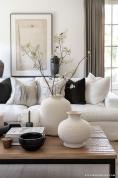 a living room filled with white furniture and lots of pillows on top of a wooden table