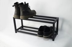 two pairs of shoes are sitting on a black shoe rack that is against a white background