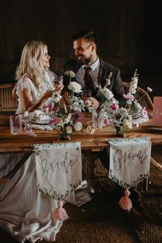 a man and woman sitting at a table with flowers