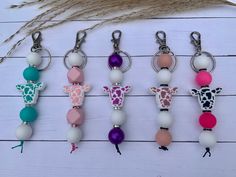 six different colored giraffe key chains on a white wooden surface