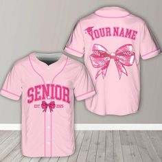 a pink baseball jersey that says your name and has a bow on the chest,