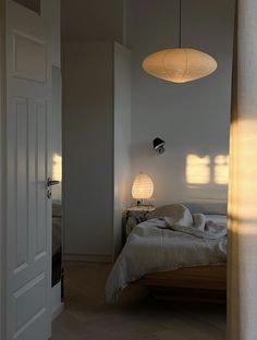 a bedroom with a bed and two lamps hanging from the ceiling