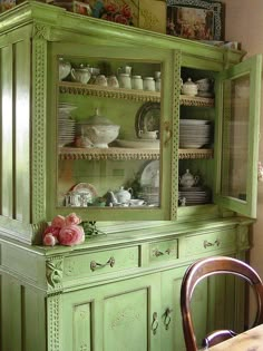 a green china cabinet with dishes on it