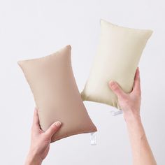 two pillows being held up in front of each other