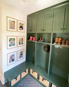 a mud room with green cabinets and pictures on the wall above it, along with baskets for shoes