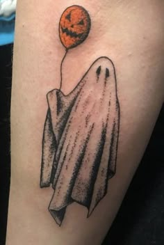 a halloween tattoo with a ghost flying through the air and an orange pumpkin on top