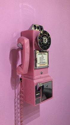 an old pink phone is hanging on the wall in front of a pink wall with a telephone