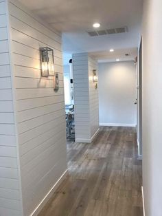 an empty room with white walls and wood flooring is seen through the doorway to another room