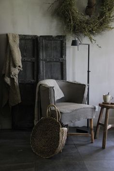 a living room with a chair, basket and coat rack in front of an old door