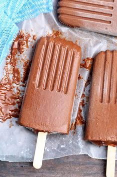 three chocolate popsicles sitting on top of a piece of wax paper next to each other