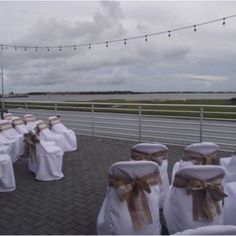 rows of white chairs with brown sashes and bows tied to them, all lined up