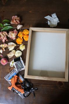 an empty wooden frame surrounded by flowers and scissors