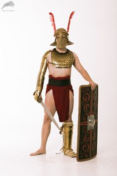 a man dressed in an ancient greek costume and holding a shield with two large spears