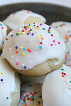 white frosted donuts with sprinkles in a black bowl on a table