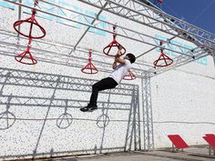 a man is performing aerial acrobatic tricks on a rope course at an event