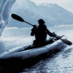 a man in a kayak paddles through the water near an ice cave,