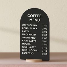 a black menu board sitting on top of a wooden table next to a white wall