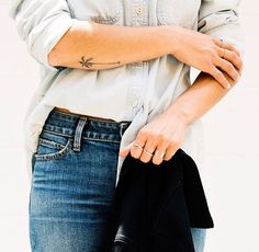 a woman in jeans and a white shirt is holding a black purse with her right hand