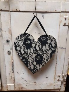 a black and white heart hanging from a hook on an old cabinet door in the shape of a flower