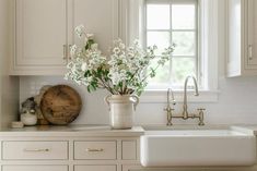 a vase with flowers sitting on top of a kitchen counter next to a white sink