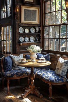 a table with two chairs and a bench in front of some large window panes