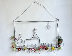 a metal wall hanging decoration with a house and trees on the outside, surrounded by flowers