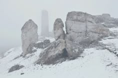 two large rocks on top of a snow covered mountain in the middle of winter time