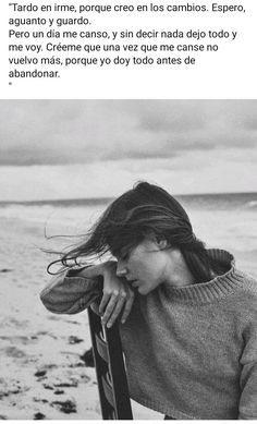 a woman standing on top of a beach next to the ocean with her hair blowing in the wind