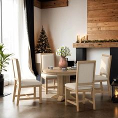 a dining room table with white chairs and a christmas tree in the corner behind it